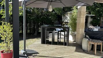 An outdoor patio area with a covered seating area, a table, and a potted plant.