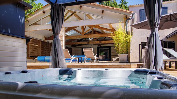 A hot tub area with a covered deck, lounge chairs, and a wooden pergola.