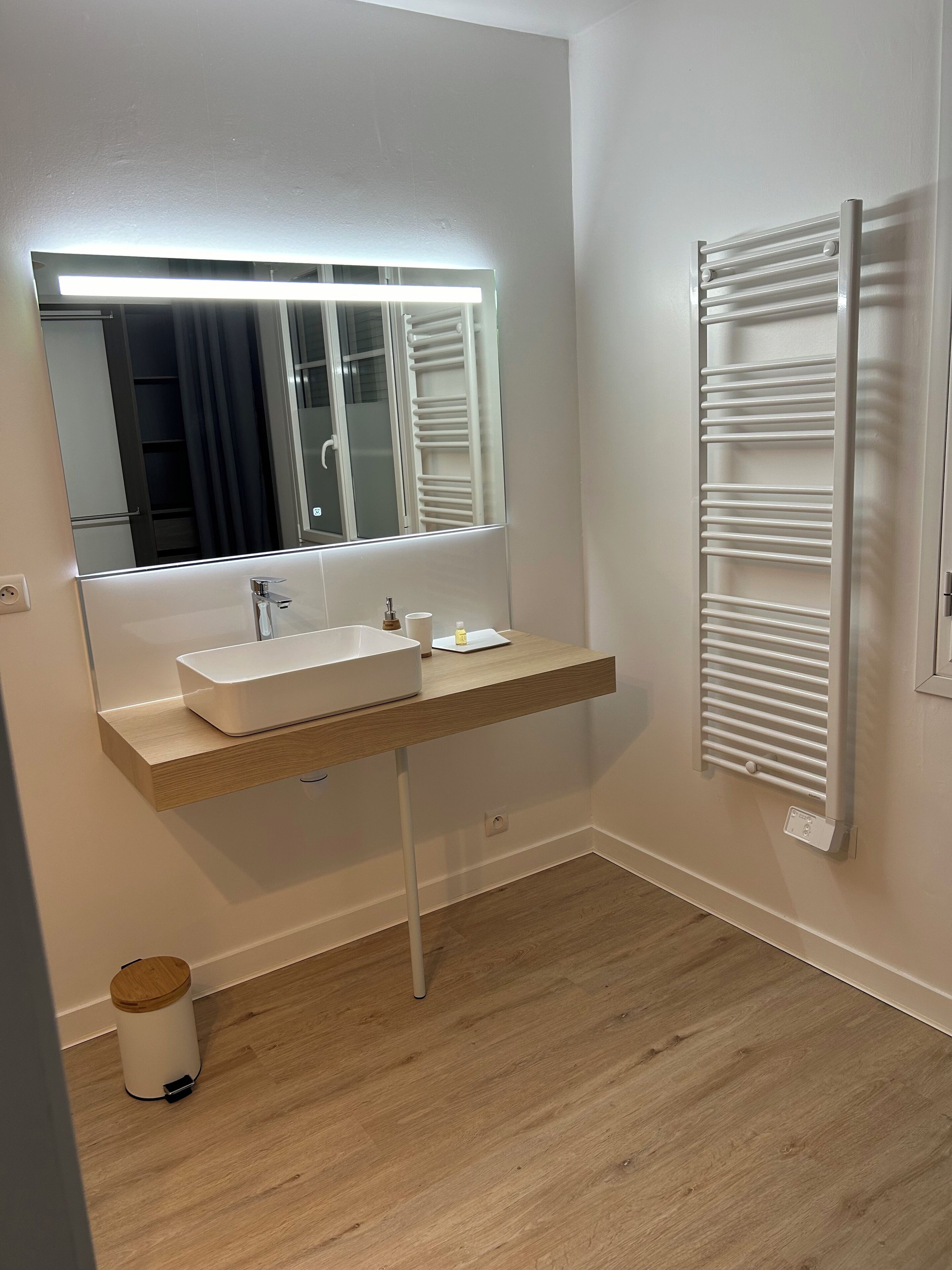 A modern bathroom with a white sink, mirror, and towel rack.