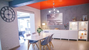 A modern kitchen with a white countertop, a clock, and a dining area with a table and chairs.