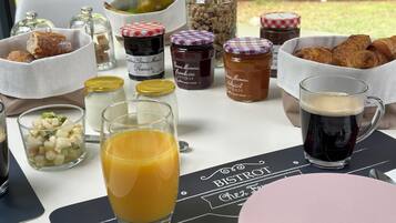 Una mesa de desayuno con diversas opciones de comida, como croissants, fruta y bebidas.