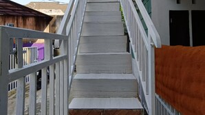 A narrow staircase with white railings leading to a building entrance. - OYO Life  92977 Neba Kost Aesthetic (Tangerang)