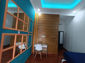 Een kamer met blauwgroene wanden, houten lambrisering, een bureau met stoel en een blauwe bank.