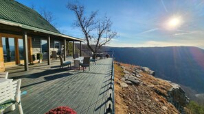 Une terrasse en bois avec des sièges extérieurs, offrant une vue sur un paysage montagneux.