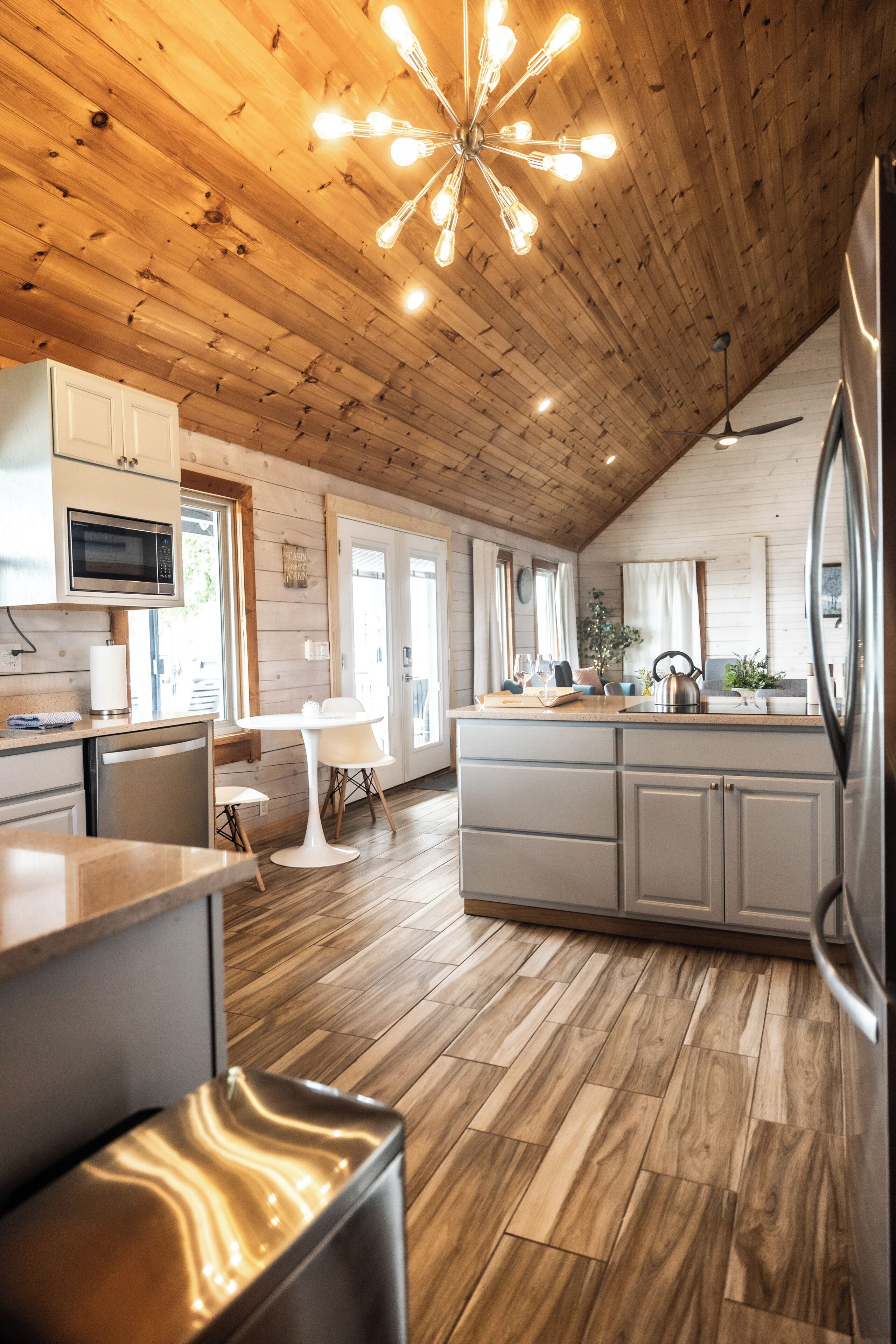 A modern kitchen with wooden flooring, a central island, and a ceiling fan.