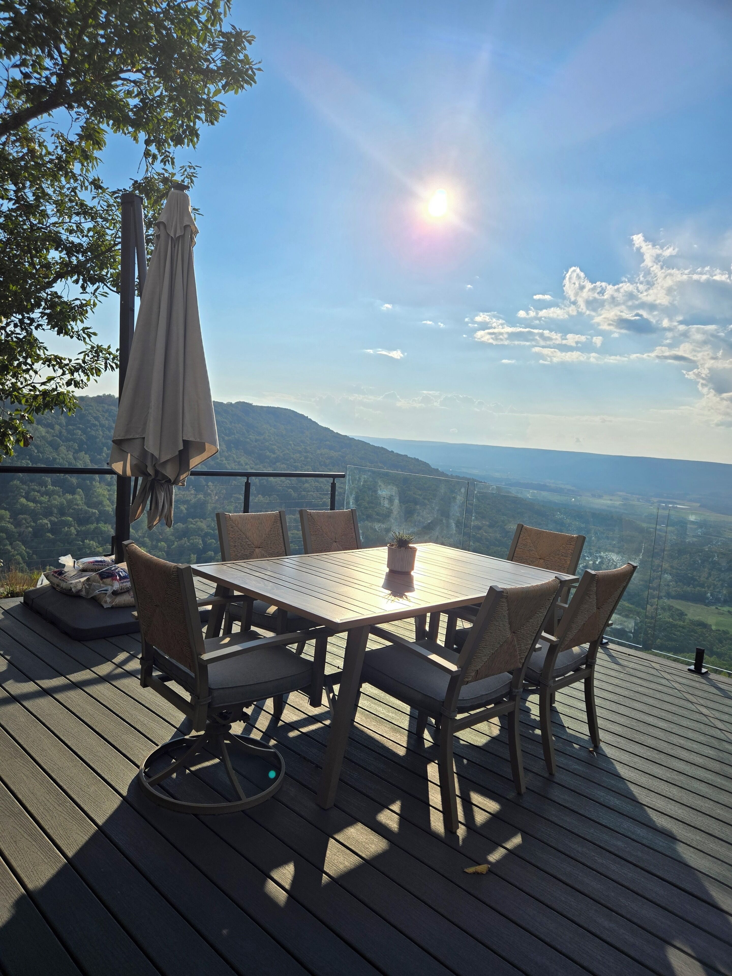 A wooden deck with a table and chairs, overlooking a scenic landscape.
