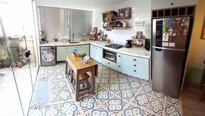 Een moderne keuken met een inbouwoven, een koelkast en een eethoek met een houten tafel.