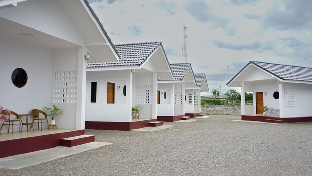 A row of white buildings with grey roofs and red trim, arranged in a courtyard with gravel ground. - Chanmuang Resort   (Phetchaburi)