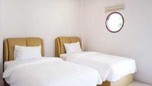 A hotel room with two beds, a round window, and a ceiling light. - Chanmuang Resort   (Phetchaburi)
