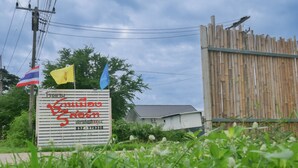 A signboard with Thai text, a Thai flag, and a blue flag. - Chanmuang Resort   (Phetchaburi)