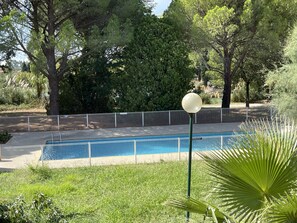 Una piscina rodeada por una cerca, con árboles y un farol en primer plano.