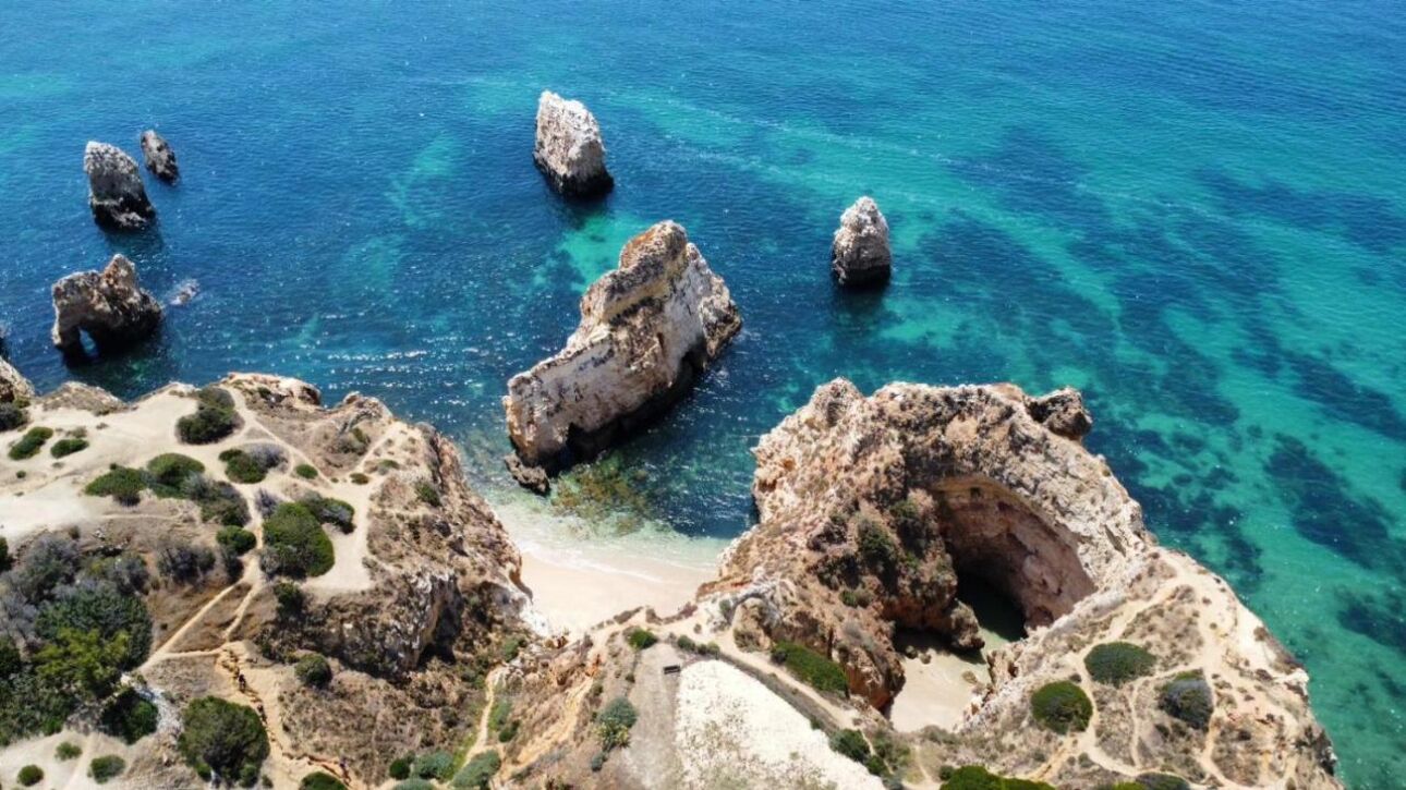 An aerial view of a coastal area with rocky formations and clear blue waters.