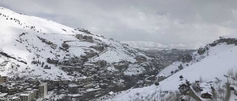 A snow-covered mountainous area with buildings and a small lake.