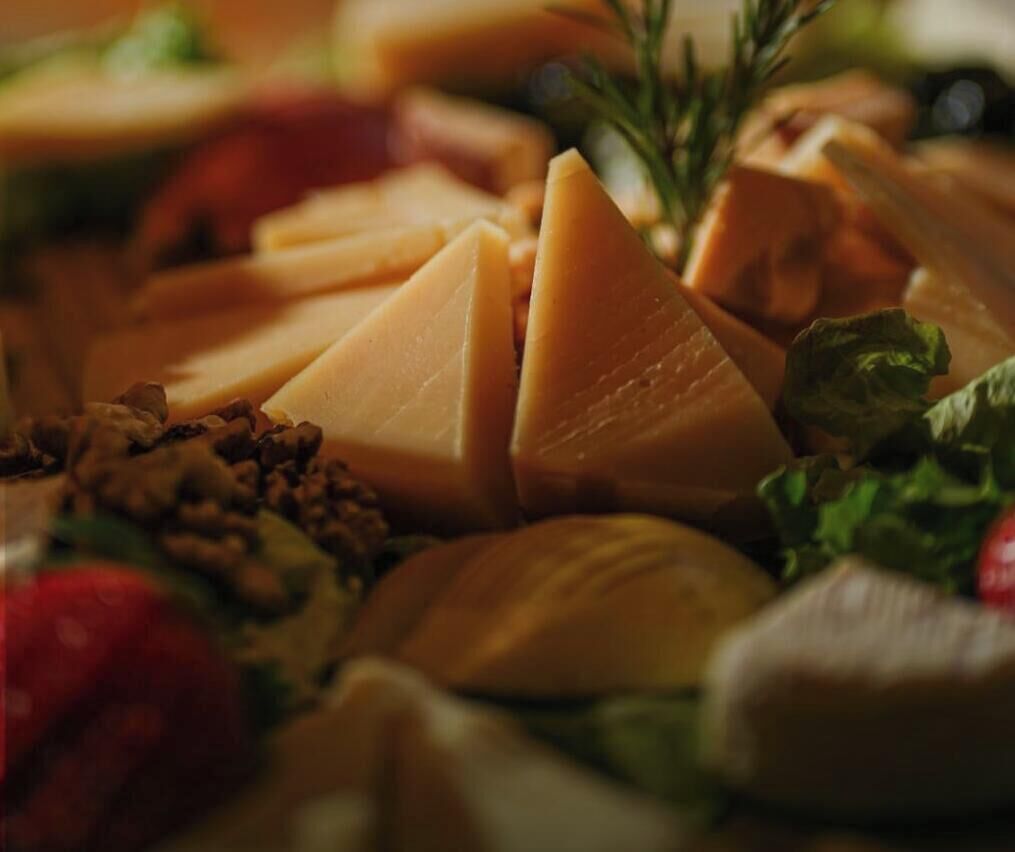 A cheese platter with various types of cheese, nuts, and greens.
