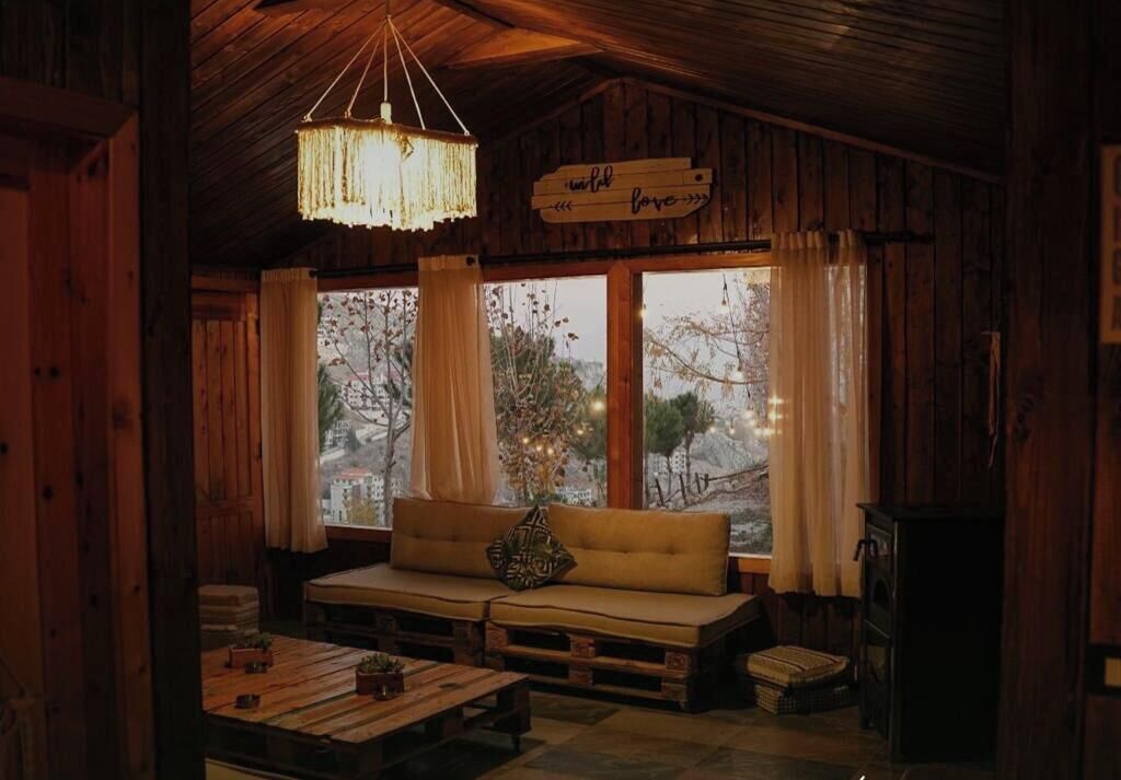 A cozy cabin interior with a wooden ceiling, a sofa with cushions, a hanging light fixture, and a sign that reads "unloved love".