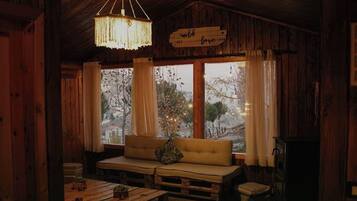 A cozy cabin interior with a wooden ceiling, a sofa with cushions, a hanging light fixture, and a sign that reads "unloved love".