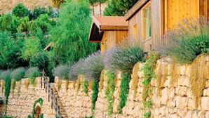 Un bâtiment rustique en bois, doté d’un mur de soutènement en pierre et d’un escalier en bois menant à l’entrée.