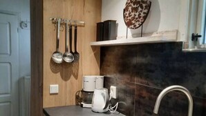 A kitchen with wooden cabinets, a stainless steel sink, a coffee maker, and a decorative plate on the wall.