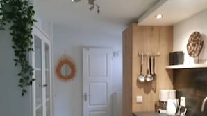 A modern kitchen with wooden cabinets, a countertop, and a sink. There is a door with a white frame and a circular decoration on the wall.