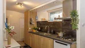 A modern kitchen with wooden cabinets, a stainless steel sink, a stove, and a window above the sink.