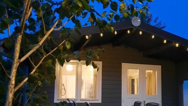 A wooden house with a patio, a table with chairs, and string lights.