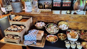 Un buffet proposant une variété de plats, notamment du pain, des salades et des desserts.