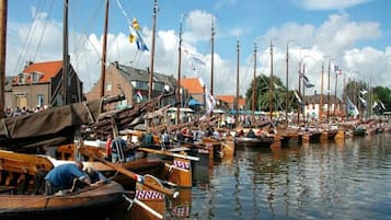 A marina with numerous wooden boats docked, a clear sky, and buildings in the background.