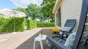 Eine Terrassengruppe im Freien mit Tisch, zwei Stühlen und einem großen Sonnenschirm.