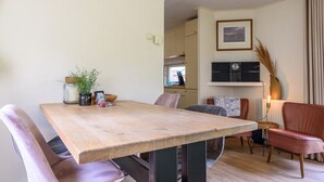 Ein Essbereich mit Holztisch, Stühlen und einer Küche im Hintergrund.