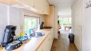 Eine moderne Küche mit Einbauherd, Spüle und Kaffeemaschine. Ein Fenster sorgt für natürliches Licht und bietet einen Blick ins Freie.