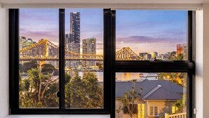 A window with a cityscape view including a bridge, buildings, and a residential area.