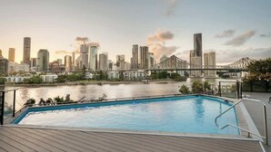 A swimming pool with a city skyline and a bridge in the background.