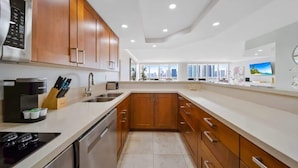 A modern kitchen with wooden cabinets, stainless steel appliances, and a large window offering a city view. - Central Long Stay Base | Gym & Balcony | StayCozy (Miami)