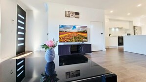 Una sala de estar moderna con un televisor de pantalla plana, una mesa de centro negra y un florero con flores.