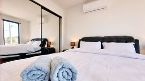 Una habitación de hotel con una cama grande, un espejo, una mesita de noche y un equipo de aire acondicionado en la pared.