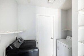 Un cuarto de lavado con lavadora, secadora y repisa.
