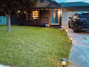 Una propiedad residencial con un césped bien cuidado, un porche cubierto y un garaje.