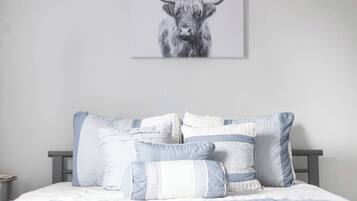 Een slaapkamer met een bed, kussens en een schilderij van een stier.