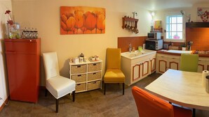 A compact kitchen with a dining area, featuring a refrigerator, a sink, a stove, and a dining table with chairs.