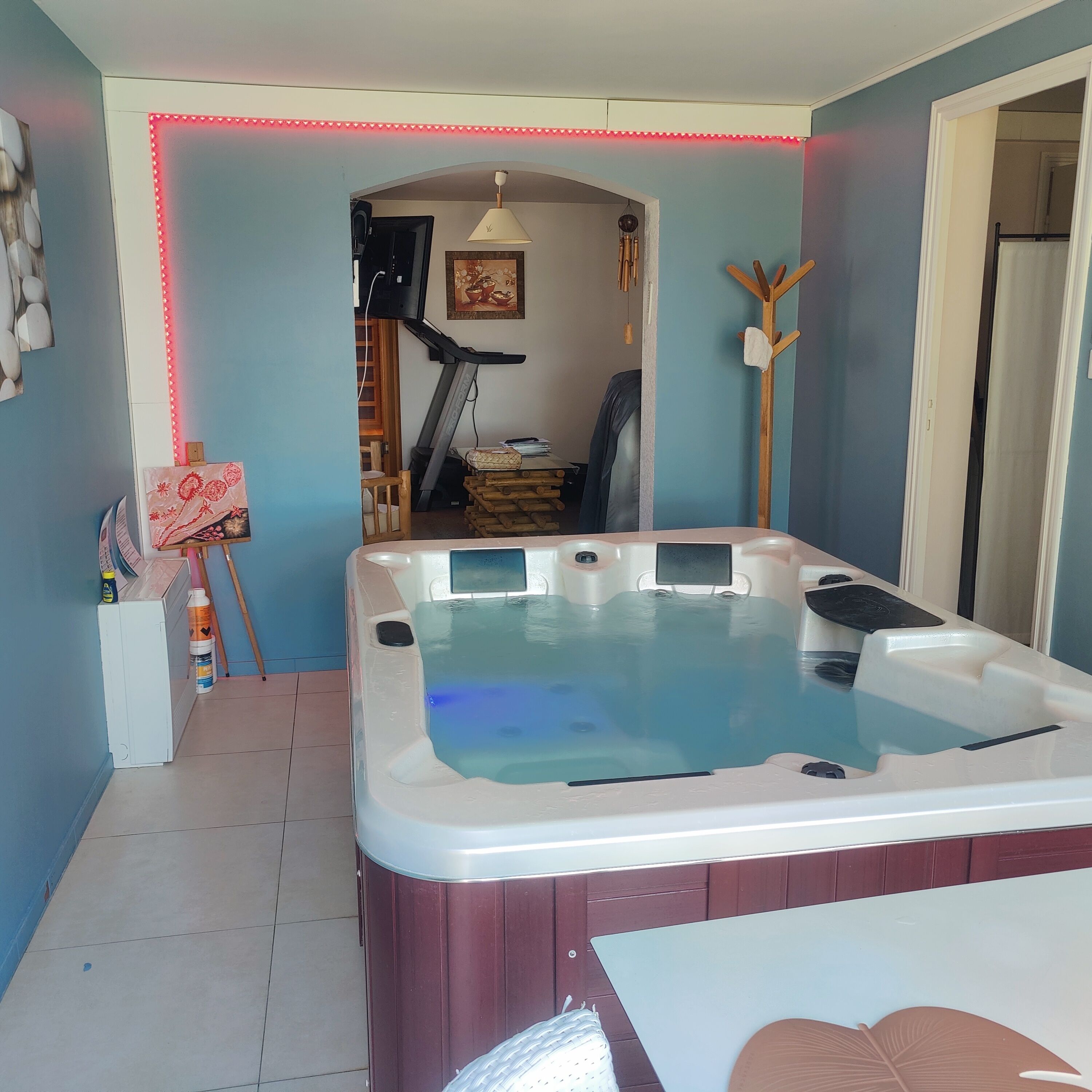 Ein Zimmer mit Whirlpool, Fitnessgeräten und einer Holzkonstruktion.