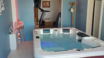 Ein Zimmer mit Whirlpool, Fitnessgeräten und einer Holzkonstruktion.