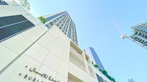 A modern building with a sign reading "Buri Royale" and a construction crane in the background. - bnbme | Burj Royale | 1 BDR (Dubai)