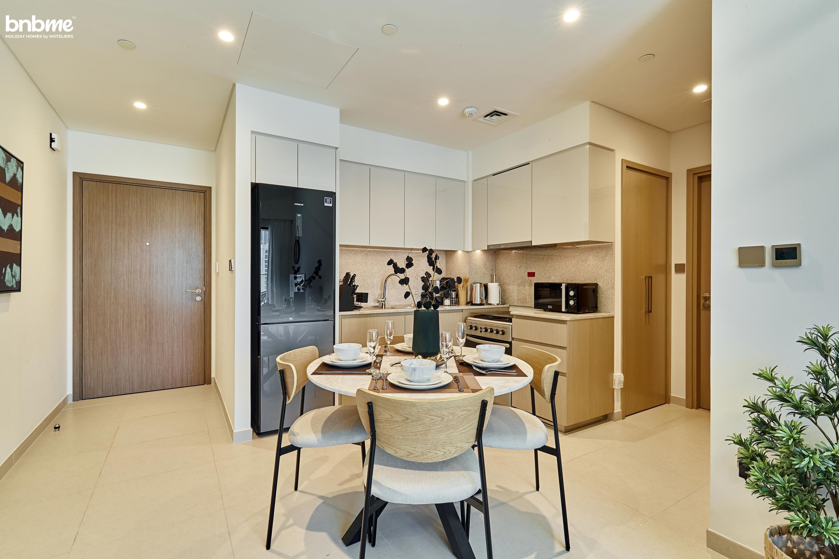 A modern kitchen with white cabinets, a black refrigerator, and a dining area with a round table set for four.