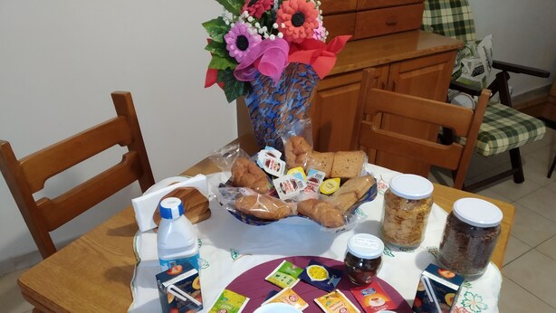 A breakfast setup with bread, pastries, and condiments on a table, accompanied by a flower arrangement and a bottle of milk. - Grandma Ida's - holiday home (Civitacampomarano)
