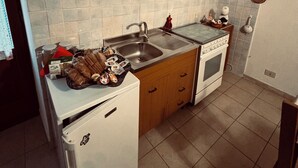 A kitchen with wooden cabinets, a white refrigerator, a sink, and a stove. - Grandma Ida's - holiday home (Civitacampomarano)