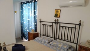 A bedroom with a bed, a nightstand, a wall-mounted air conditioner, and a curtain with a celestial pattern. - Grandma Ida's - holiday home (Civitacampomarano)