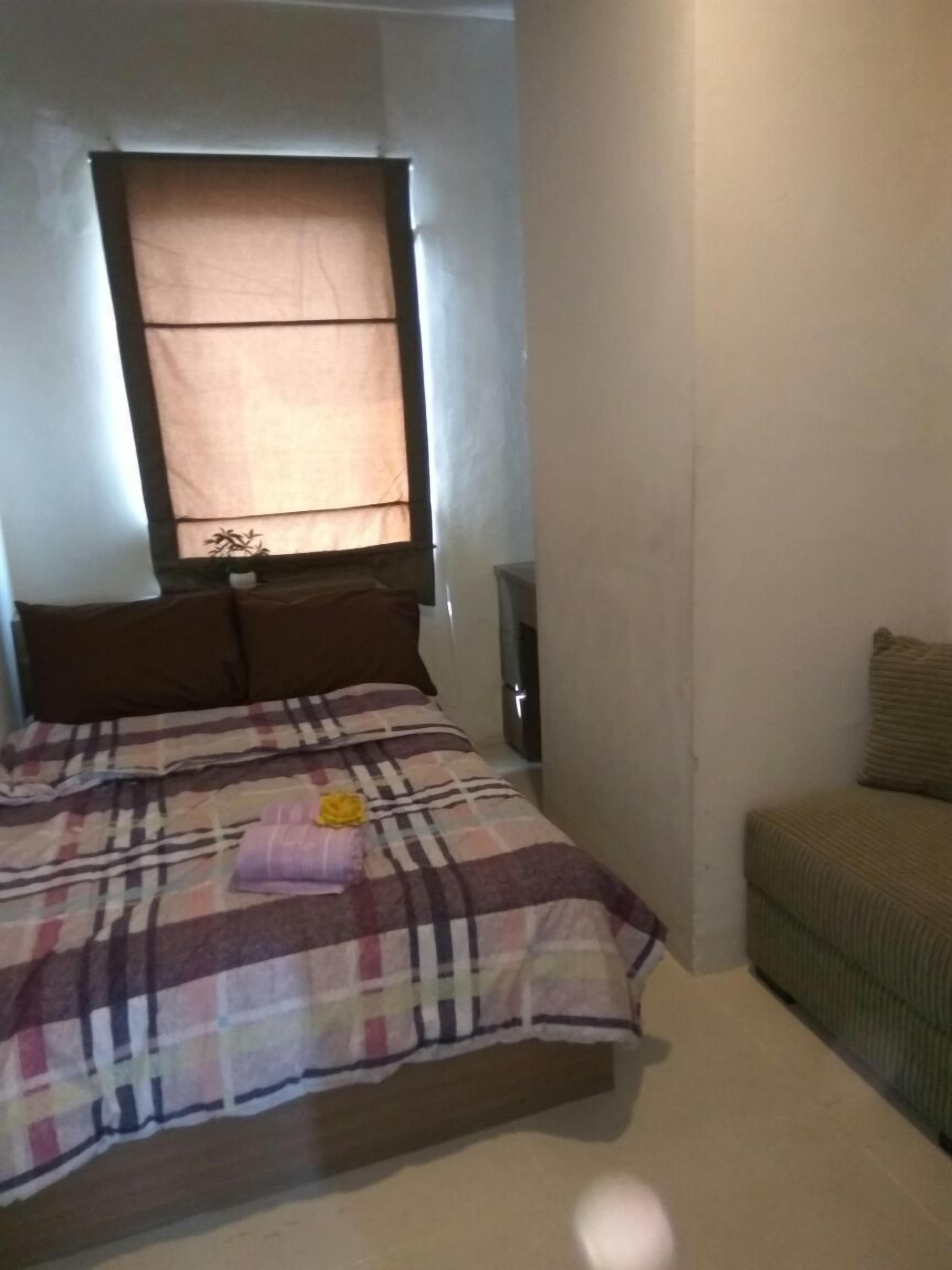 Un dormitorio con cama, una ventana con persianas, una mesita de noche y un sofá.