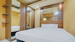 Una cama bien tendida con sábanas blancas en una habitación de hotel con paneles de madera y un espejo grande sobre la cama.