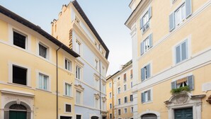 A narrow street with buildings featuring classic architecture, including arched doorways and decorative moldings. - Amazing Fontana di Trevi (Roma)