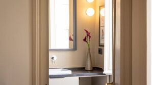 A bathroom with a white sink, a mirror, and a vase with flowers. - Amazing Fontana di Trevi (Roma)